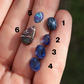 Blue gemstones on a hand with numbers indicating their order.