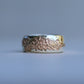 Two-tone ring with textured surface on a gray background