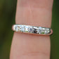 Silver ring with small diamonds on a finger against a blurred green background
