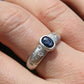 Silver ring with a blue gemstone on a finger